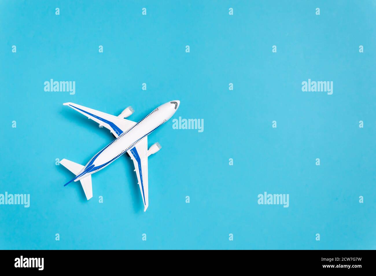 Aeroplano bianco su sfondo blu con spazio di copia per il testo. Concetto di viaggio minimo. Composizione in stile piatto per agenzia di viaggio o compagnia aerea Foto Stock