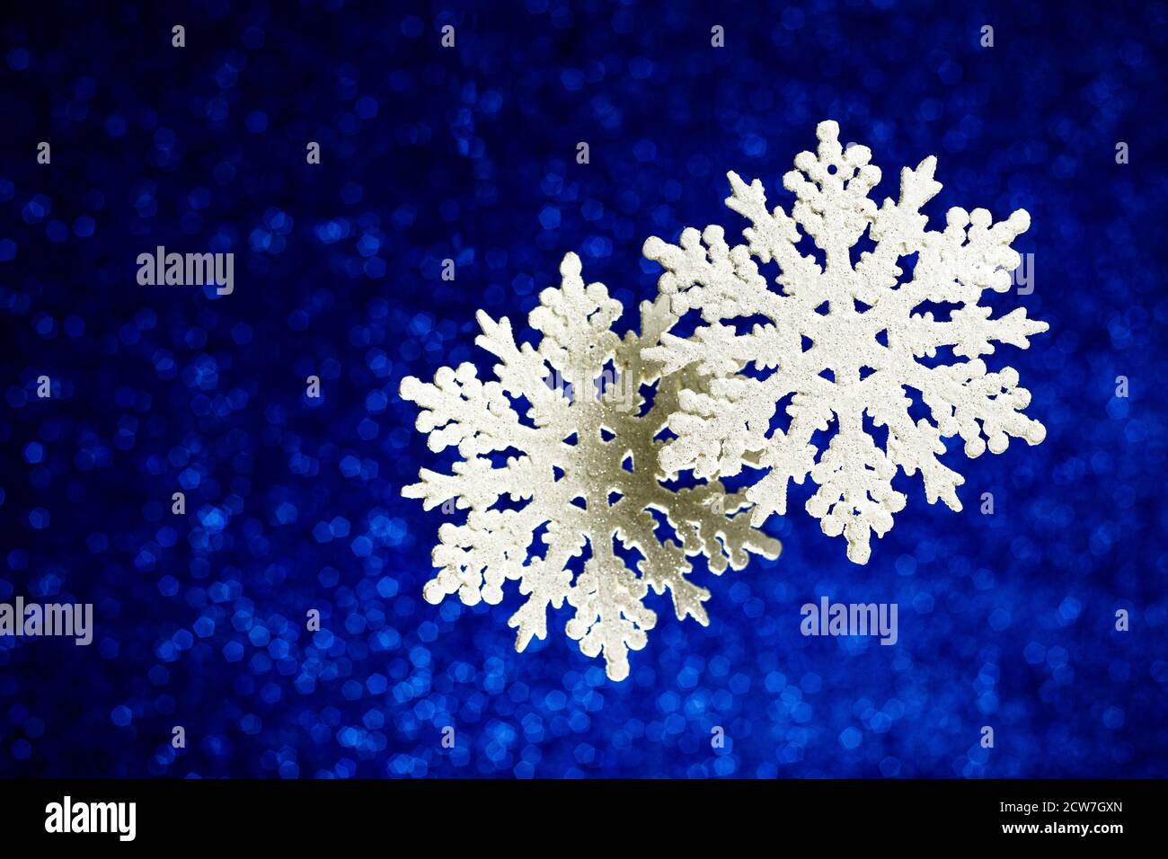 Fiocchi di neve decorativi su glitter e sfondo blu lucido classico. Natale e Capodanno decorazione blu trendy. Foto Stock