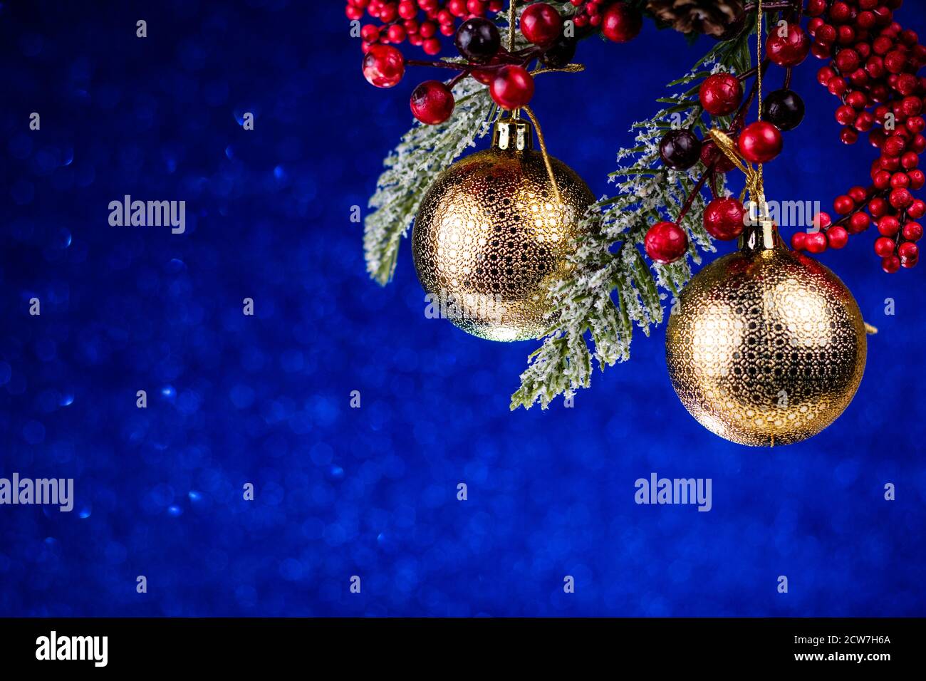 Palle d'oro dell'albero di Natale e bacche rosse su glitter e brillano su sfondo blu classico. Vacanze invernali stile retrò composizione. Natale e Nuova Y Foto Stock