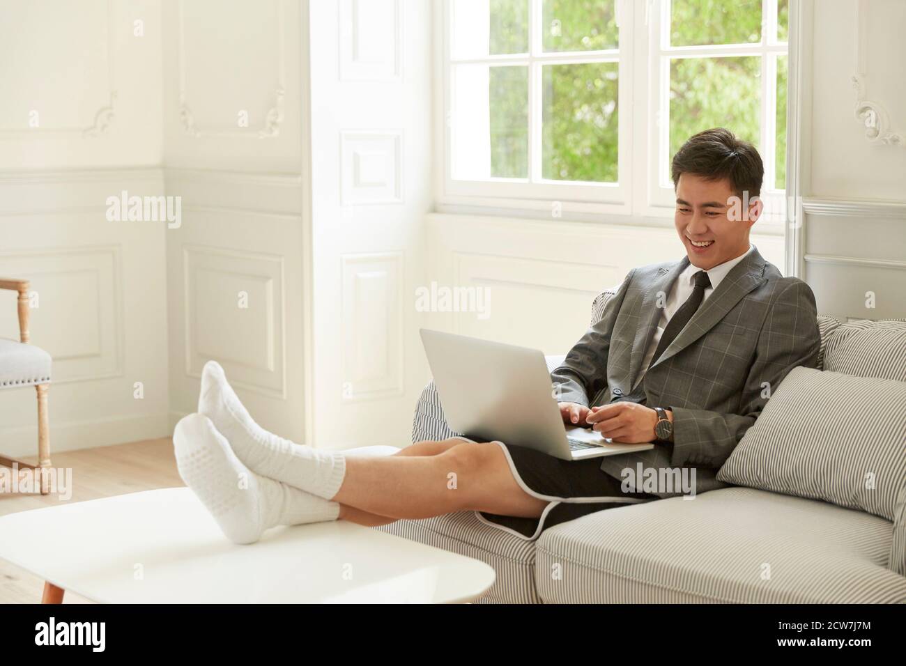 giovane uomo d'affari asiatico che indossa abiti e pantaloncini da lavoro riunione a casa con i colleghi online utilizzando la chat video sul computer portatile computer Foto Stock