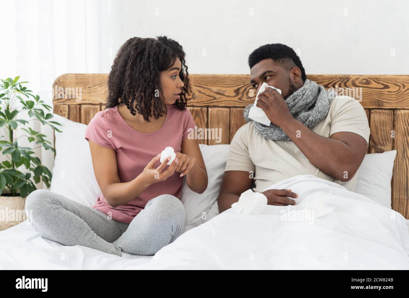 Malato afroamericano avvolto in sciarpa seduto a letto Foto Stock