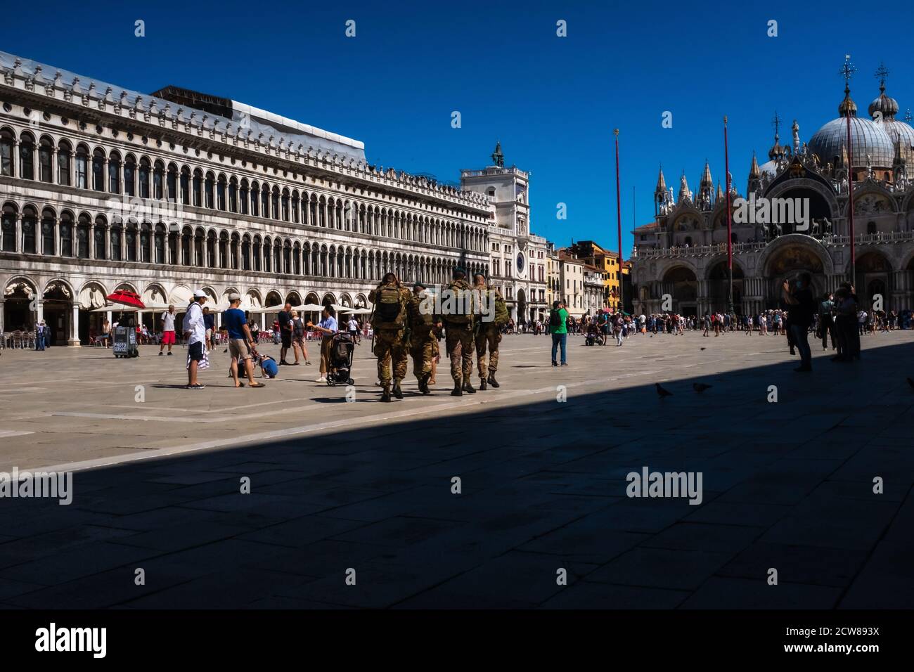 Vista posteriore di alcuni soldati dell'esercito italiano che attraversano Piazza San Marco a Venezia. Camminano in direzione del lato nord della piazza, amo Foto Stock