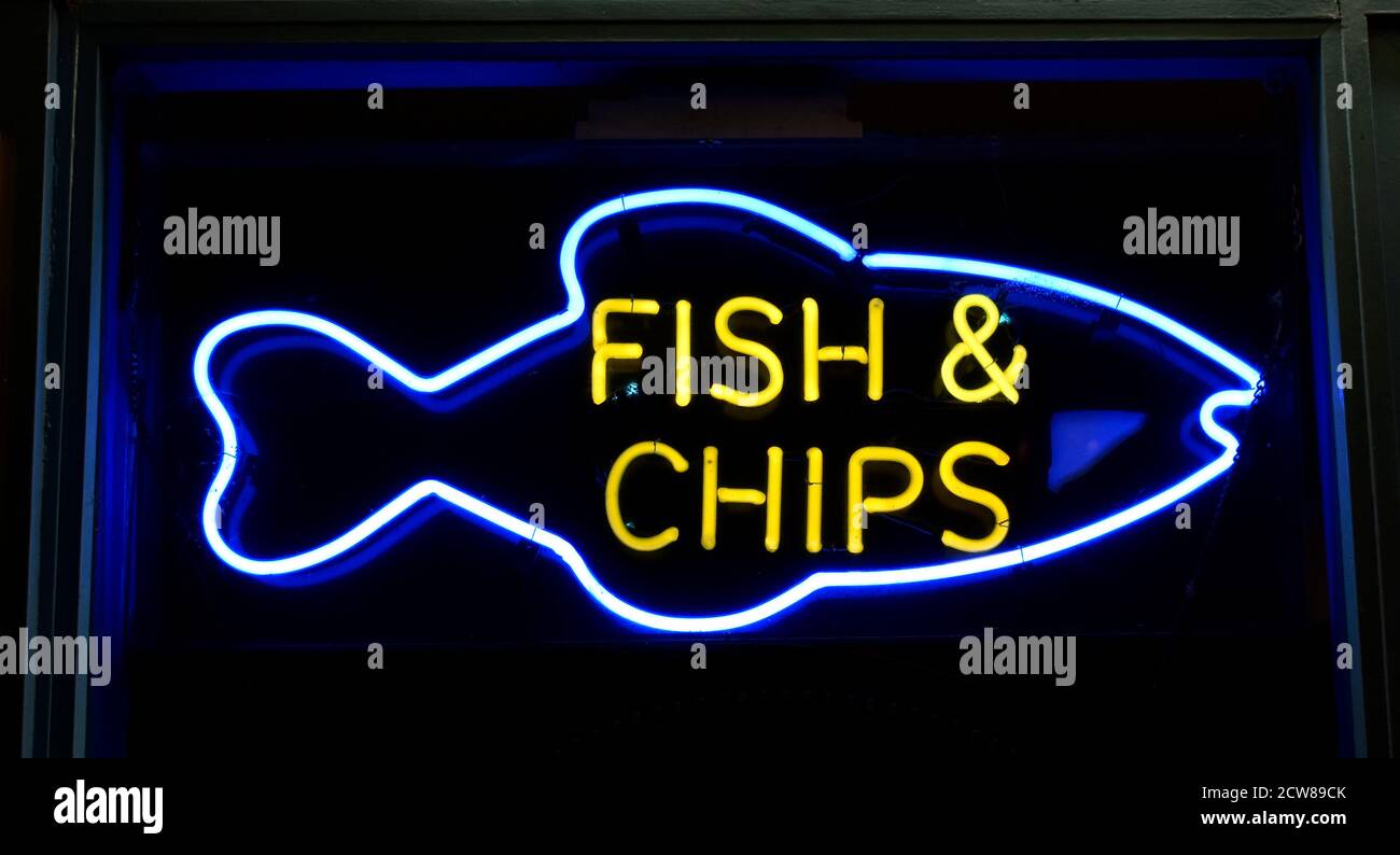 Il pesce al neon e le patatine firmano nella finestra del negozio di alimentari da asporto, Olney, Buckinghamshire, UK. Foto Stock