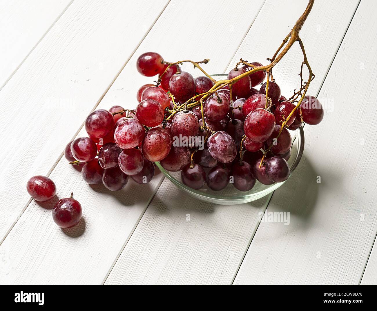 un mazzo di uve rosa su un tavolo di legno bianco Foto Stock