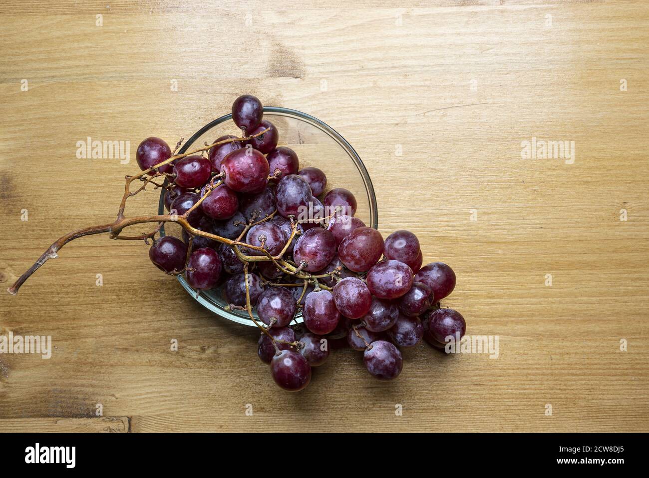 un mazzo di uve rosa su un tavolo di legno Foto Stock