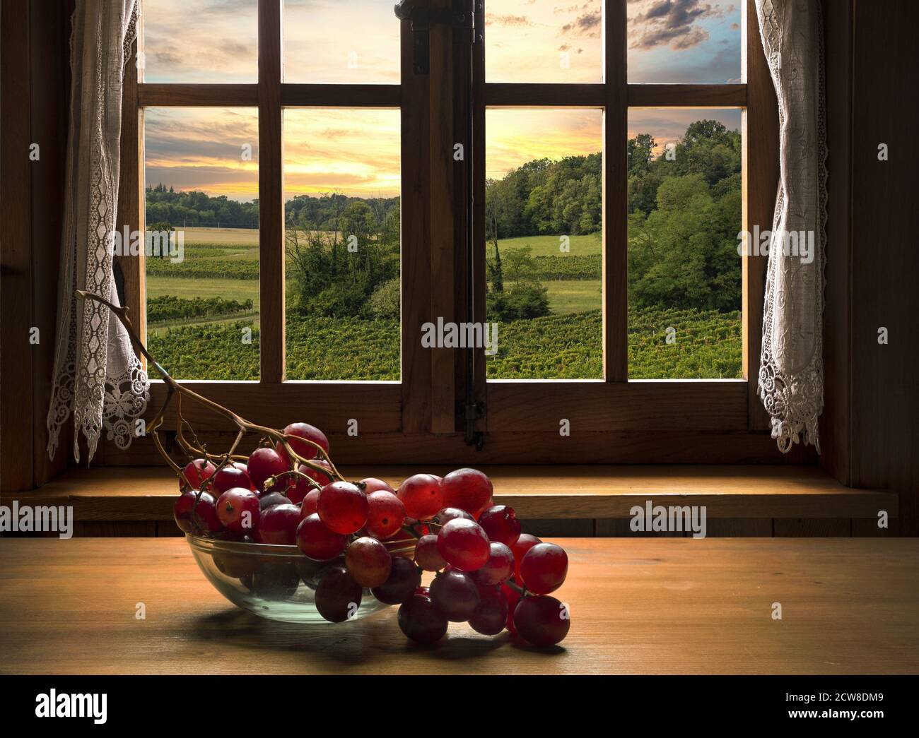 un mazzo di uve rosa su un tavolo di legno davanti della finestra Foto Stock