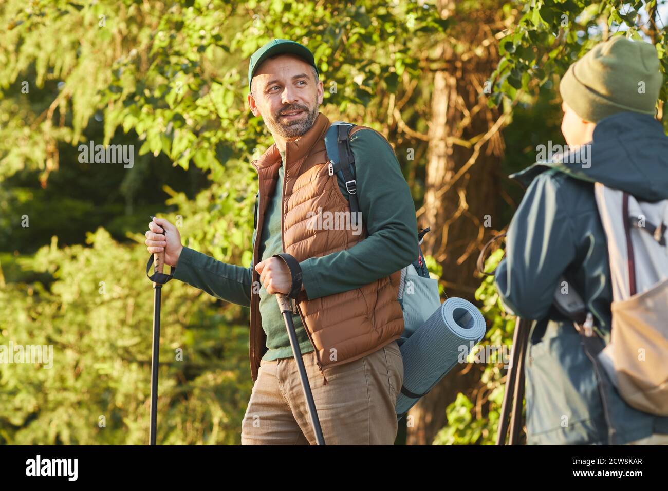 Ritratto di felice padre e figlio camminando insieme e parlando mentre camminando nella foresta con i pali, spazio di copia Foto Stock