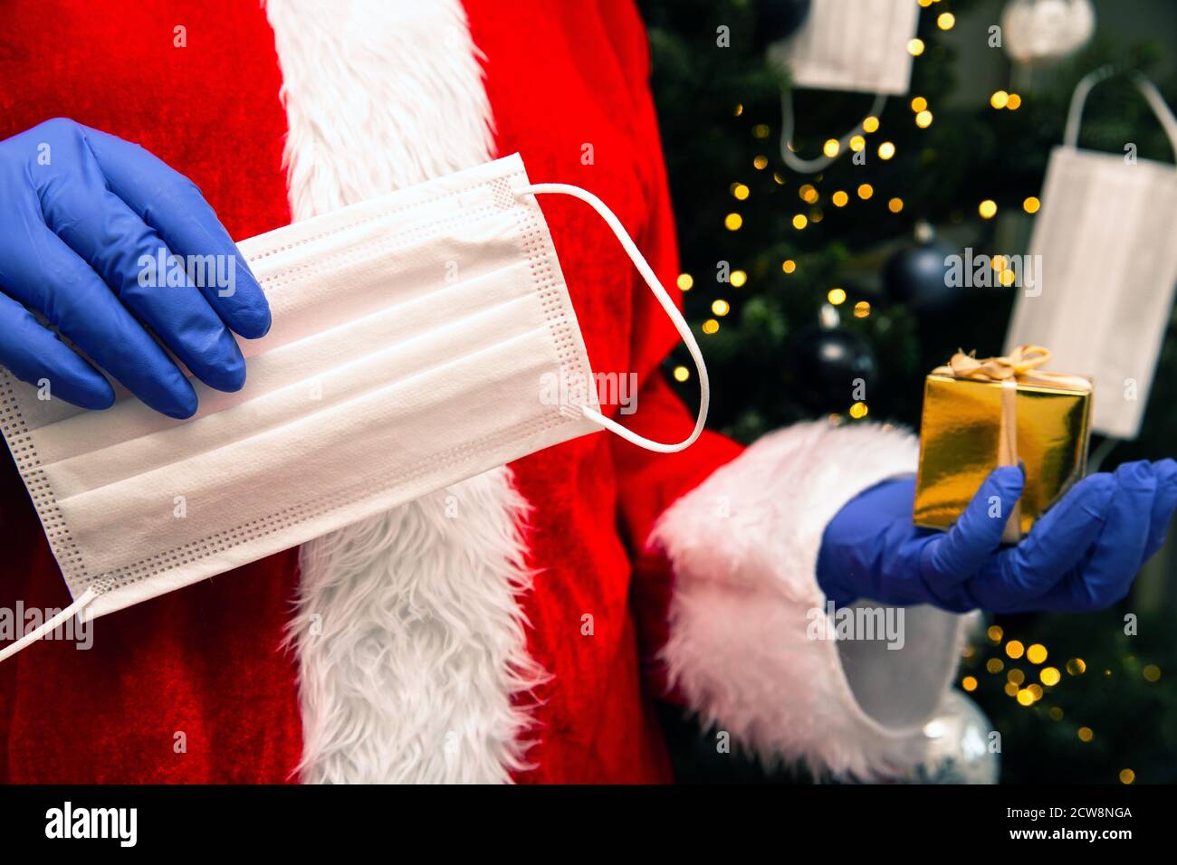 Babbo Natale con guanti e maschera viso per Coronavirus dall'albero di  Natale, che tiene un regalo d'oro, Covid-19 e il concetto di sicurezza  Natale Foto stock - Alamy