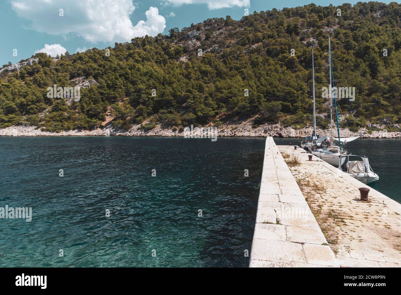 Barche a vela ancorate al molo di pietra per la protezione da forti venti e onde alla spiaggia di Stiniva sulla splendida isola di Hvar, Croazia Foto Stock