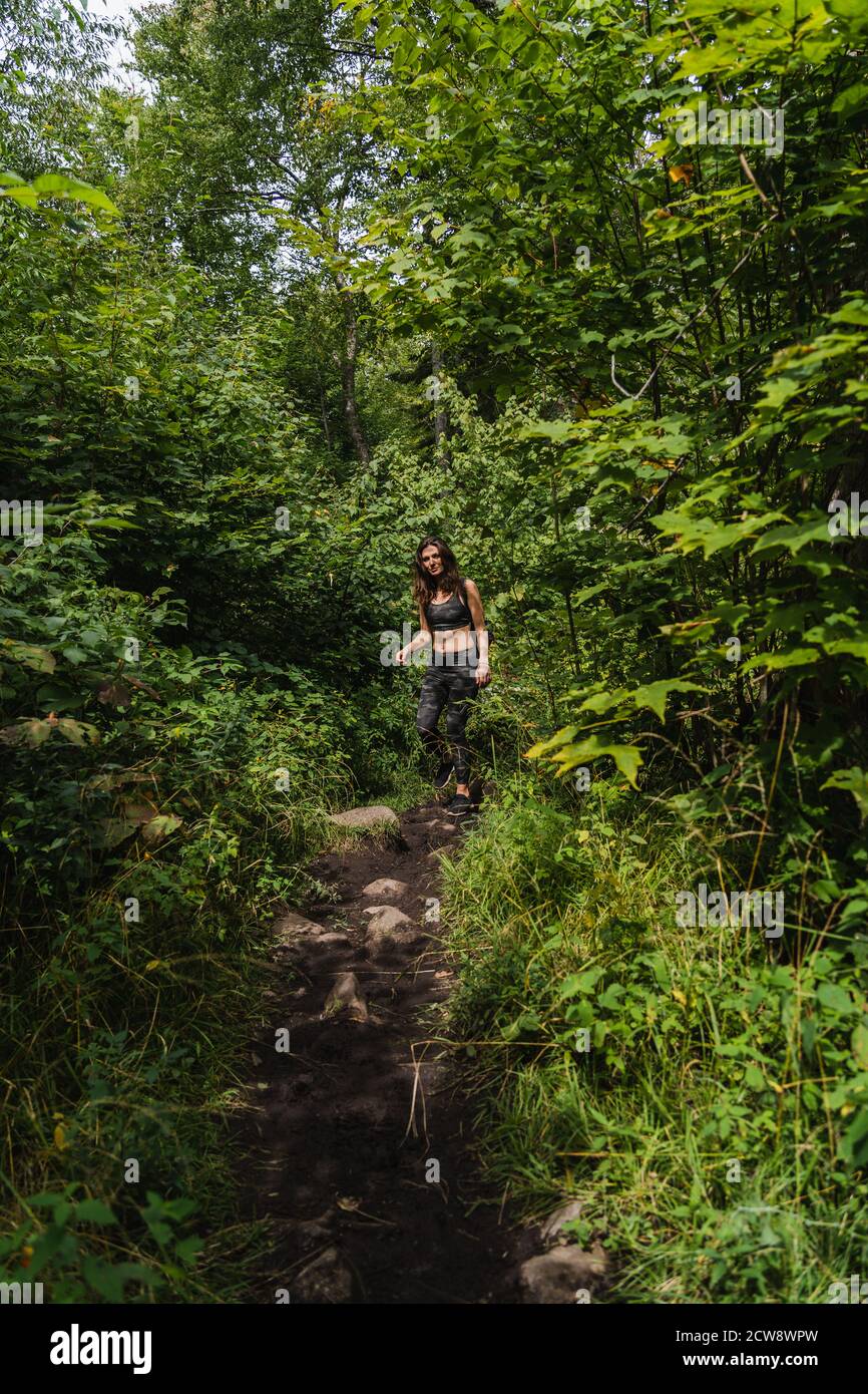 Una giovane donna che camminano su un sentiero nel Adirondacks Foto Stock