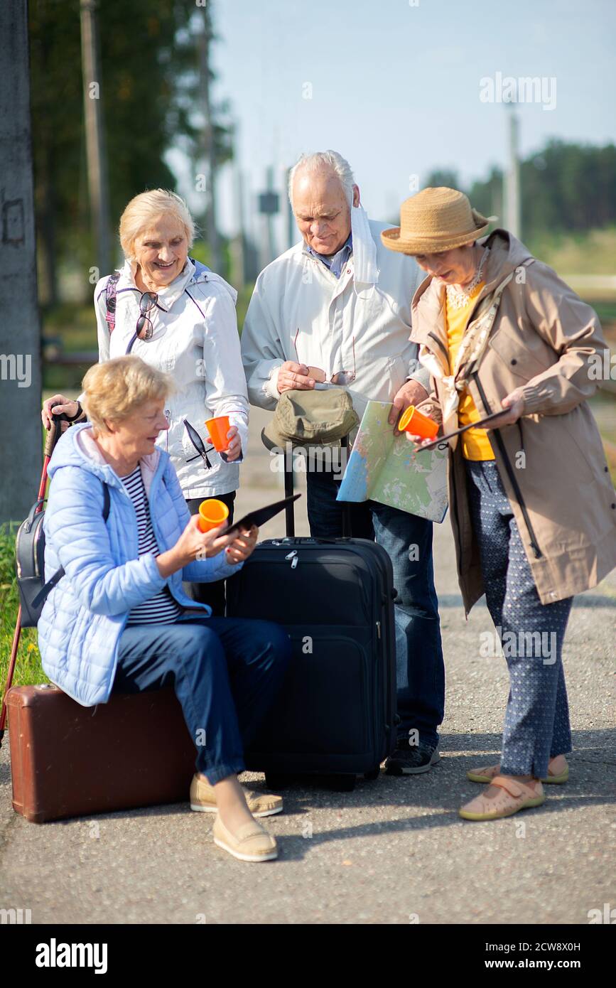 Gruppo di anziani positivi che guardano alla mappa del viaggio durante la pandemia.COVID-19 viaggio nella nuova normalità. Foto Stock