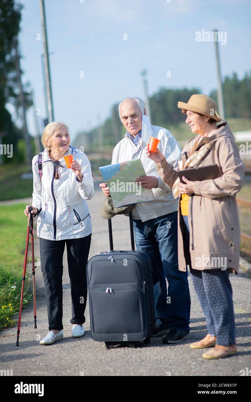 Gruppo di anziani positivi che guardano alla mappa del viaggio durante la pandemia.COVID-19 viaggio nella nuova normalità. Foto Stock
