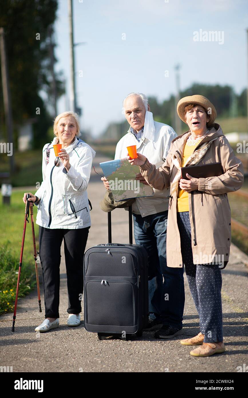 Gruppo di anziani positivi che guardano alla mappa del viaggio durante la pandemia.COVID-19 viaggio nella nuova normalità. Foto Stock