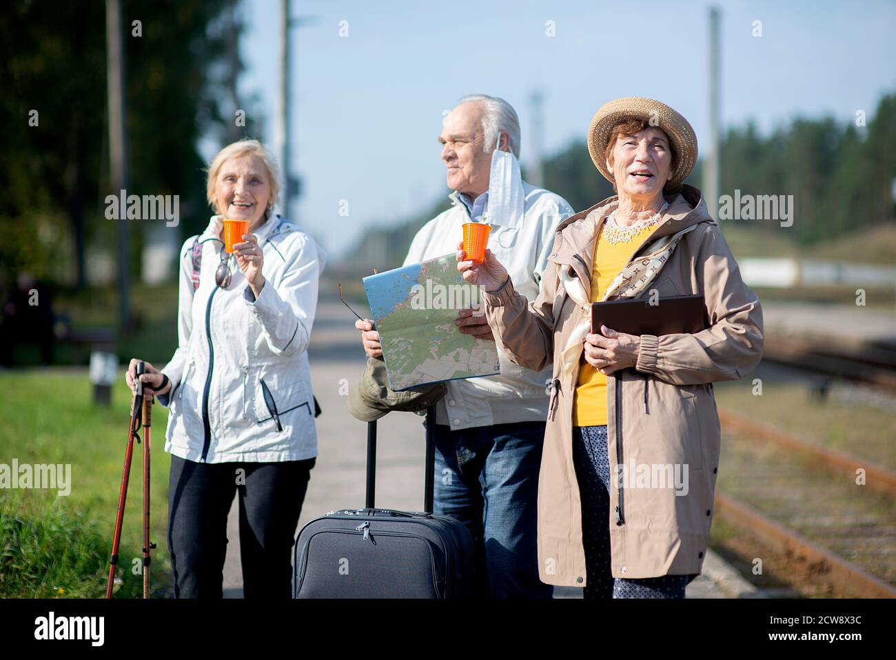 Gruppo di anziani positivi che guardano alla mappa del viaggio durante la pandemia.COVID-19 viaggio nella nuova normalità. Foto Stock