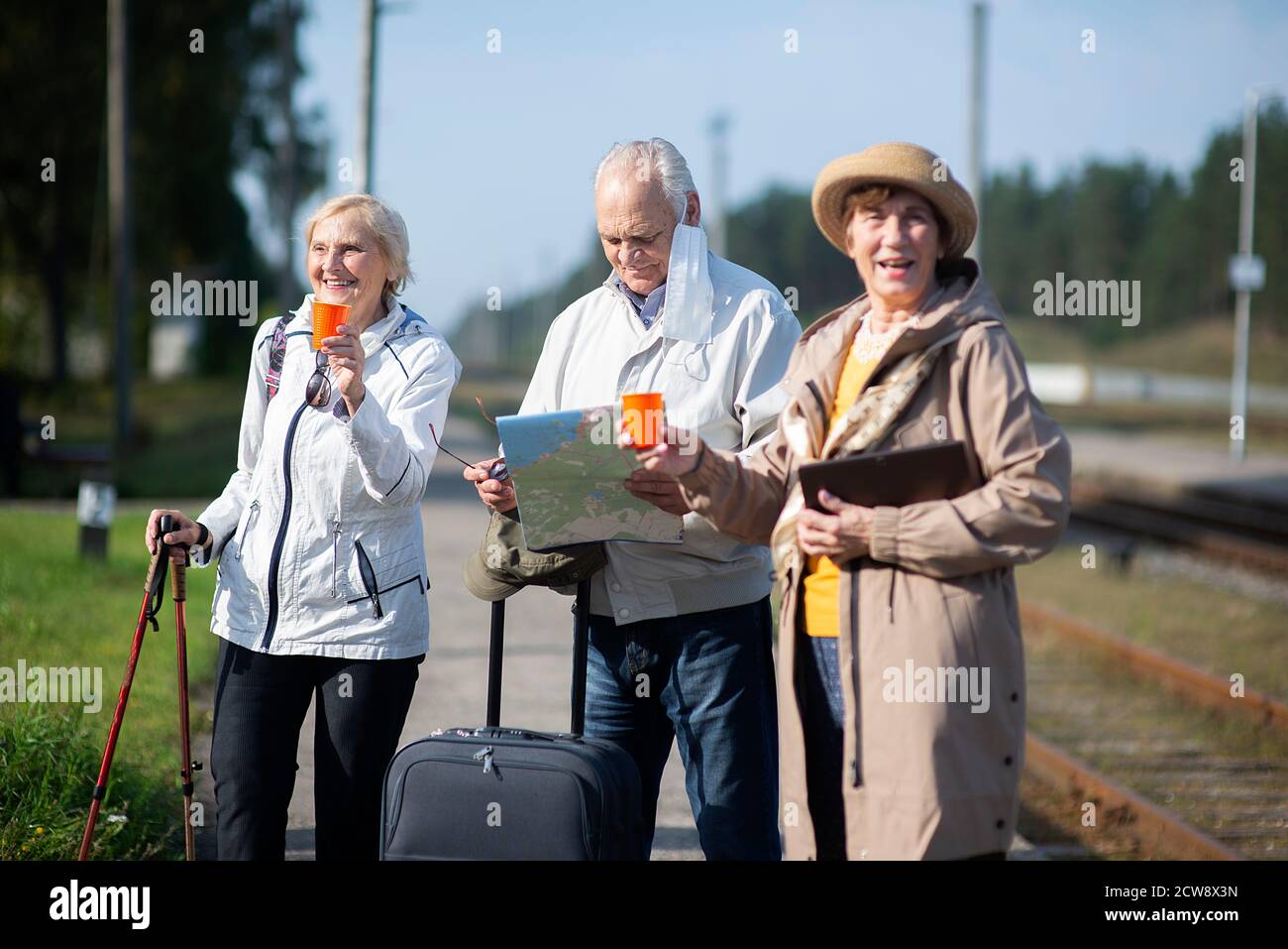 Gruppo di anziani positivi che guardano alla mappa del viaggio durante la pandemia.COVID-19 viaggio nella nuova normalità. Foto Stock