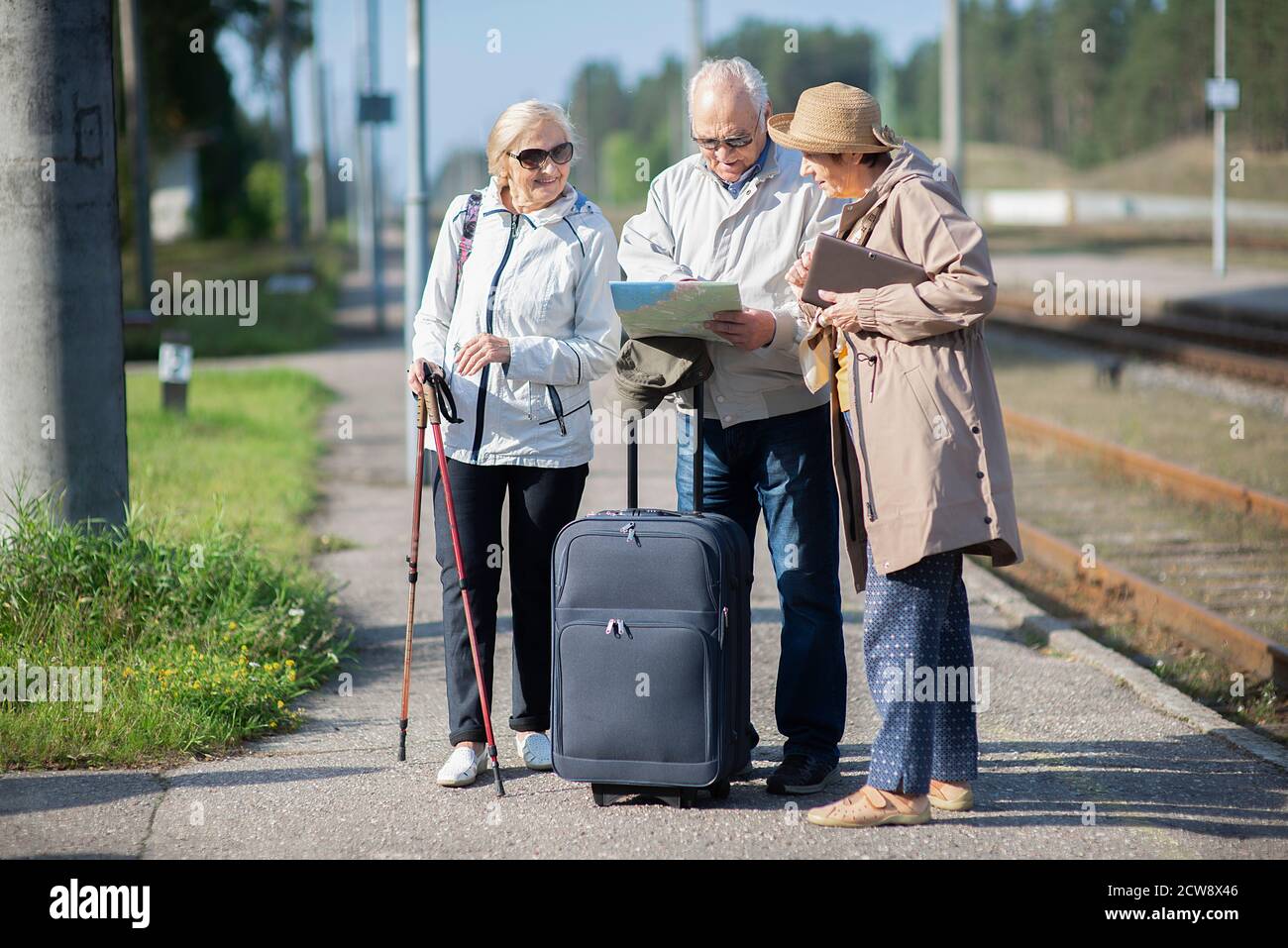 Gruppo di anziani positivi che guardano alla mappa del viaggio durante la pandemia.COVID-19 viaggio nella nuova normalità. Foto Stock