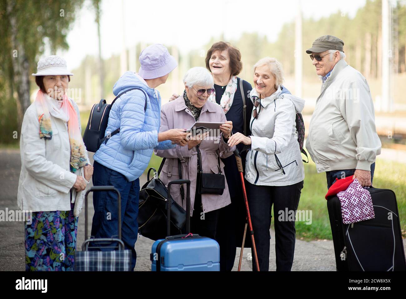 Gruppo di anziani anziani positivi che guardano alla mappa digitale del viaggio durante la pandemia.COVID-19 viaggio nella nuova normalità. Foto Stock
