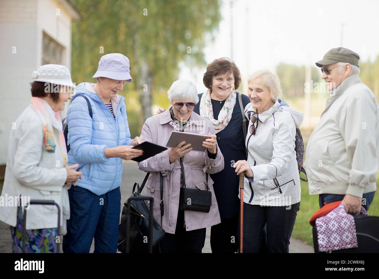 Gruppo di anziani anziani positivi che guardano alla mappa digitale del viaggio durante la pandemia.COVID-19 viaggio nella nuova normalità. Foto Stock
