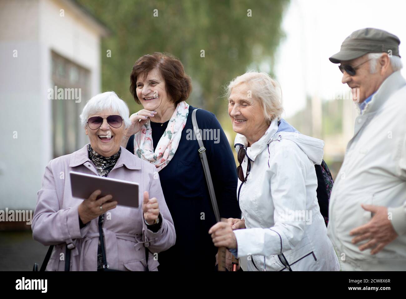 Gruppo di anziani anziani positivi che guardano alla mappa digitale del viaggio durante la pandemia.COVID-19 viaggio nella nuova normalità. Foto Stock