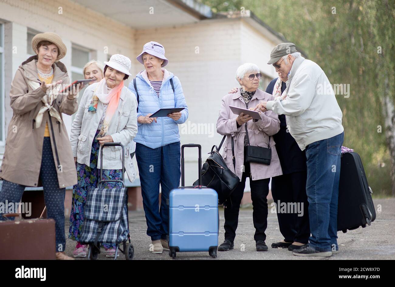 Gruppo di anziani anziani positivi che guardano alla mappa digitale del viaggio durante la pandemia.COVID-19 viaggio nella nuova normalità. Foto Stock