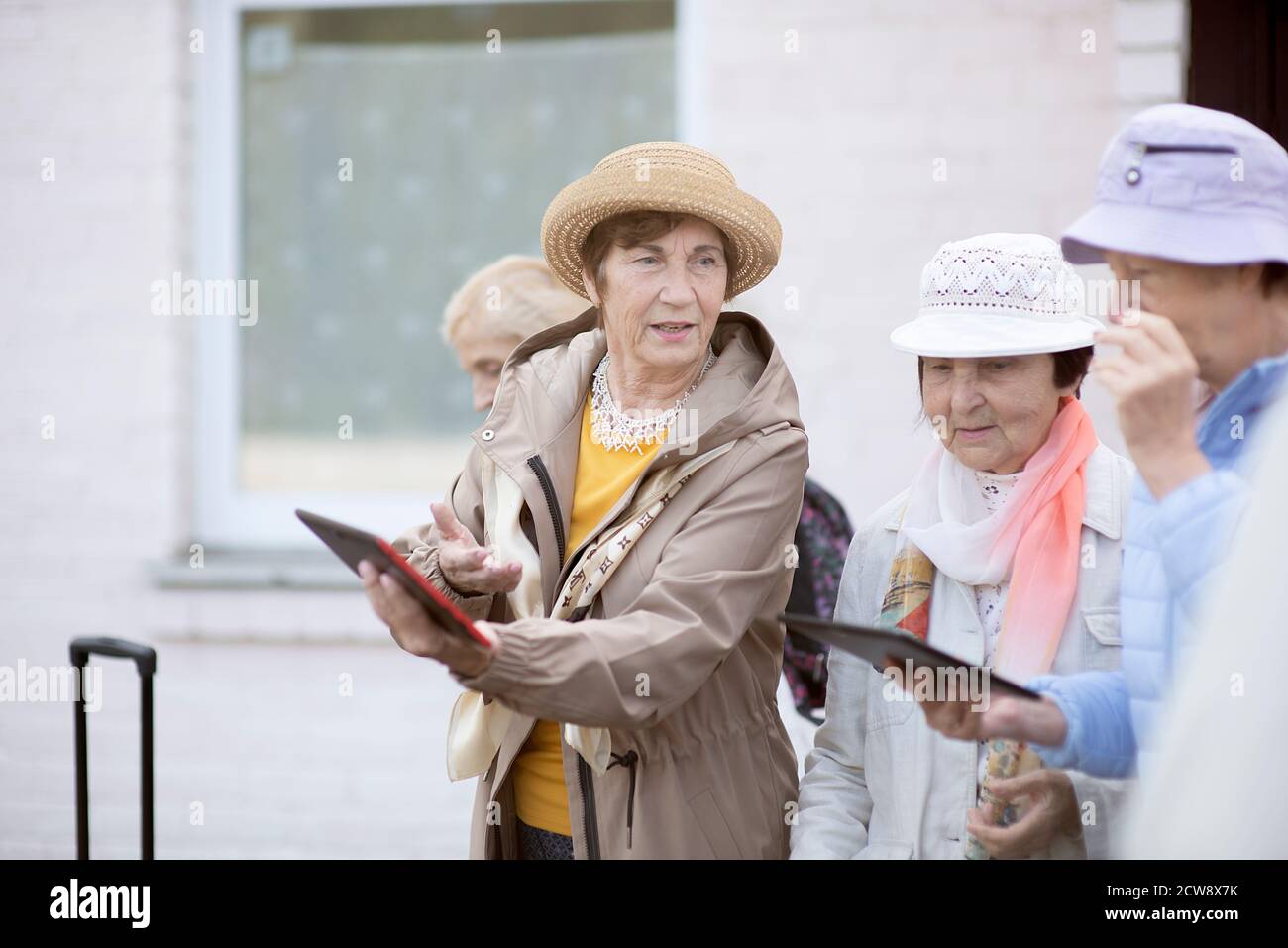 Gruppo di donne anziane positive che guardano alla mappa digitale del viaggio durante la pandemia.COVID-19 viaggio nella nuova normalità. Foto Stock