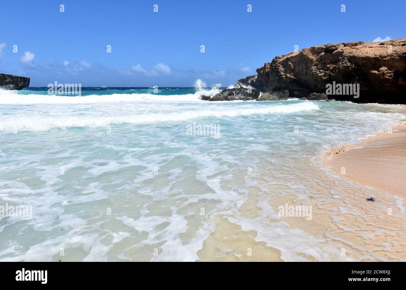 Le onde si infrangono e arrivano a riva su una spiaggia di Aruba. Foto Stock