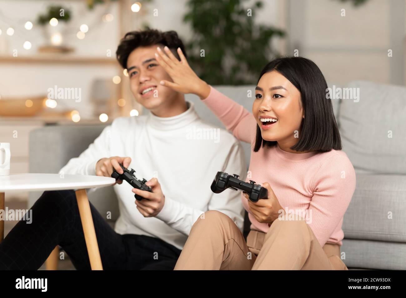 Coniugi giapponesi giocando Giochi per computer seduti sul divano a casa Foto Stock