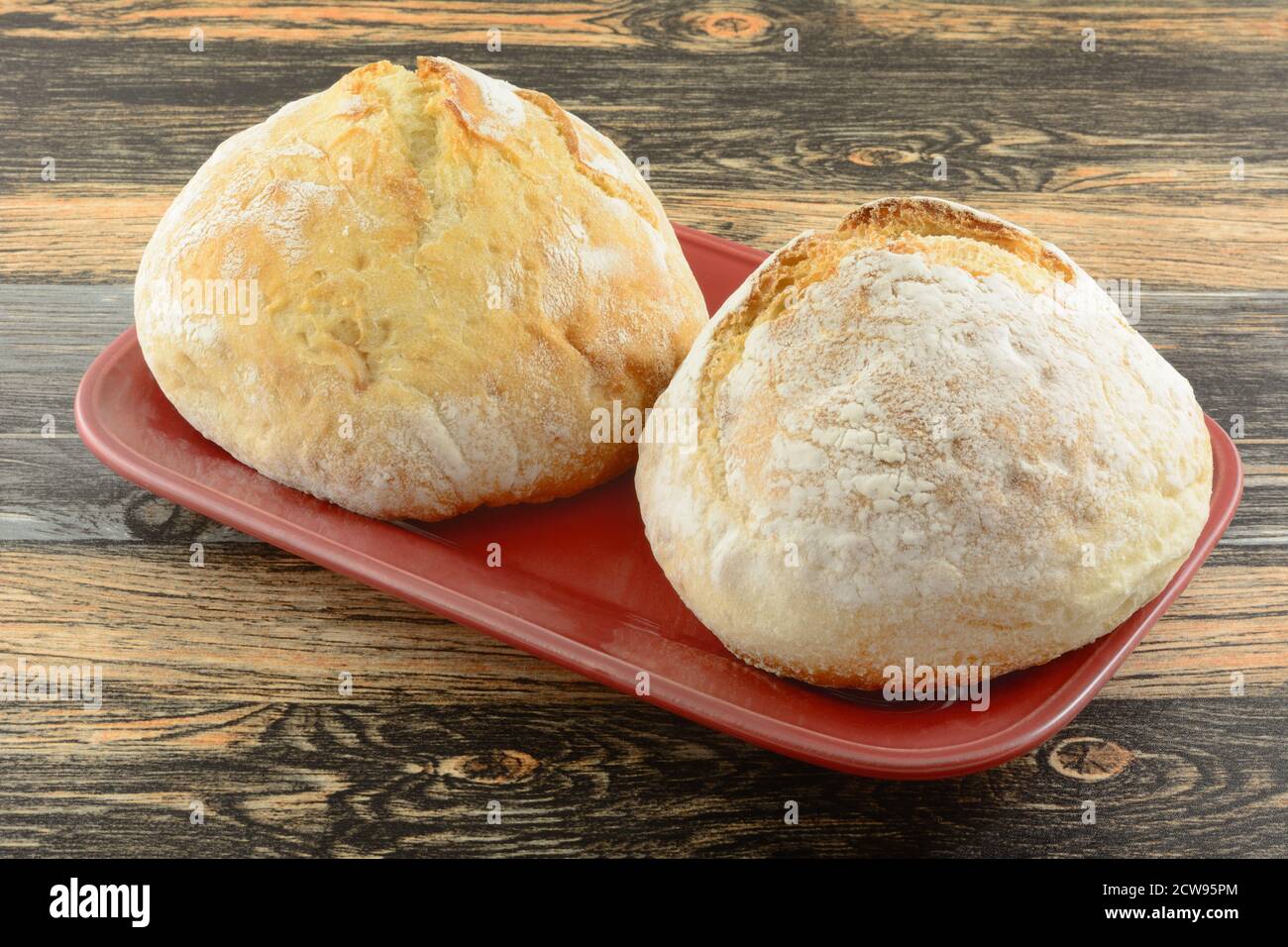 Due piccole focacce rotonde di pane francese su portata rossa piatto Foto Stock