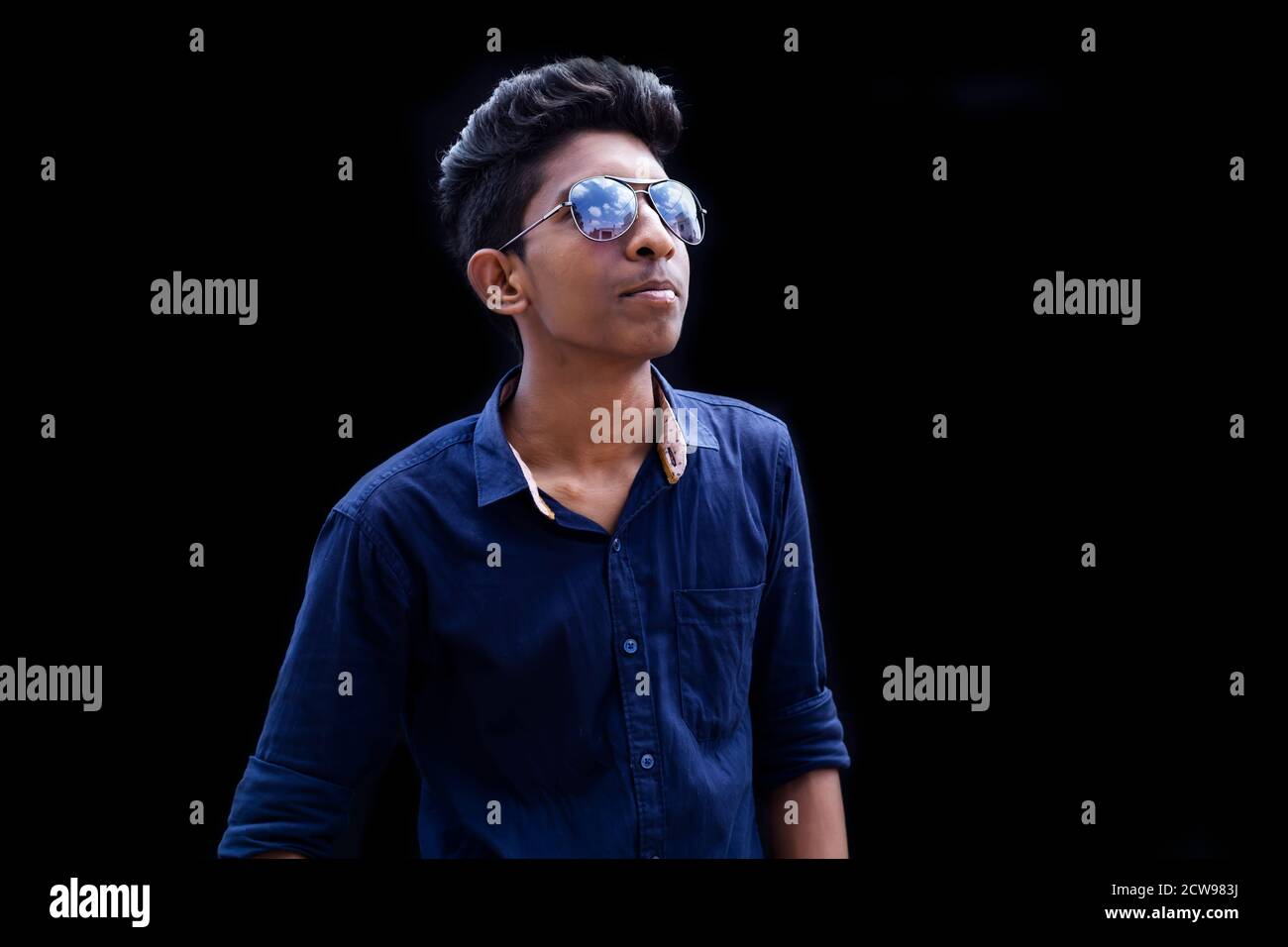 Bell'uomo elegante con camicia a plaid e occhiali da sole in posa sfondo nero Foto Stock