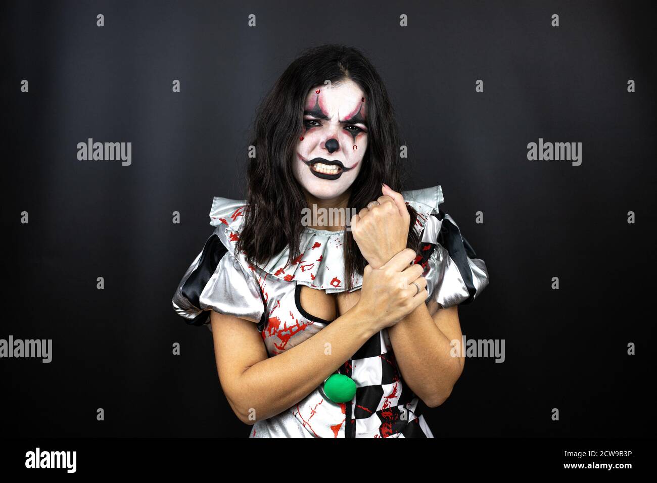 donna in un costume di clown halloween su sfondo nero isolato che soffre di dolore alle mani e alle dita, infiammazione dell'artrite Foto Stock