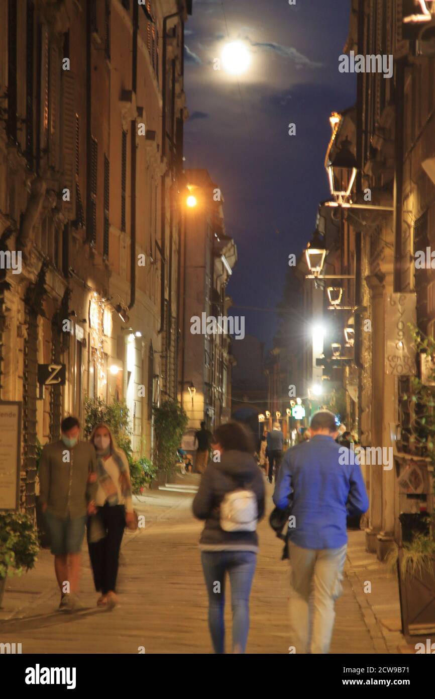 I turisti camminano sotto la luna piena attraverso le strade di Sarzana, una città di origine romanica Foto Stock