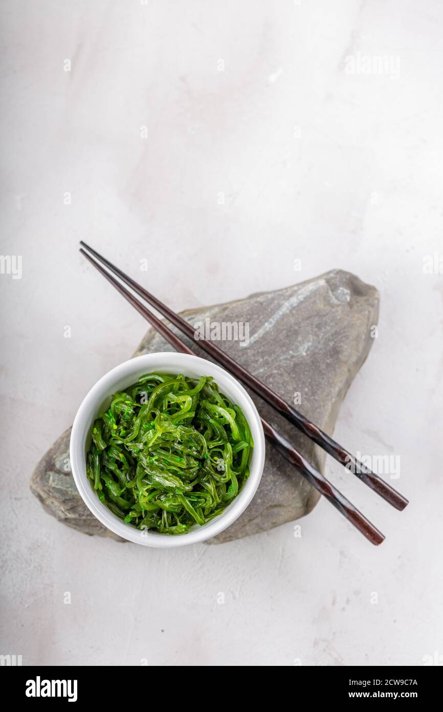 Foto ritagliata di insalata verde di alghe di wakame con bastone il ristorante Foto Stock