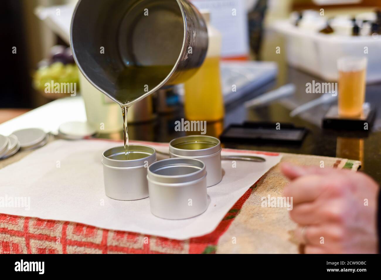 Occupazione creativa di fabbricazione della candela che mostra il versamento di liquido cera in vasi Foto Stock
