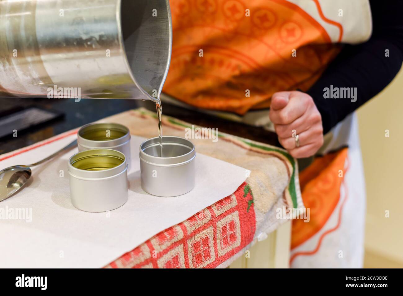 Occupazione creativa di fabbricazione della candela che mostra il versamento di liquido cera in vasi Foto Stock