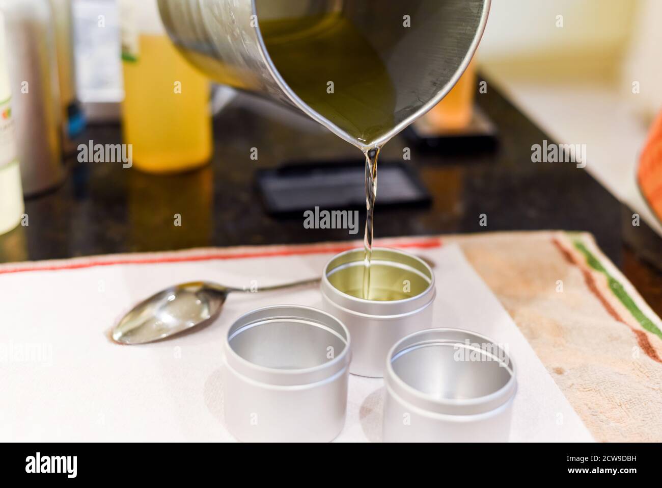 Occupazione creativa di fabbricazione della candela che mostra il versamento di liquido cera in vasi Foto Stock