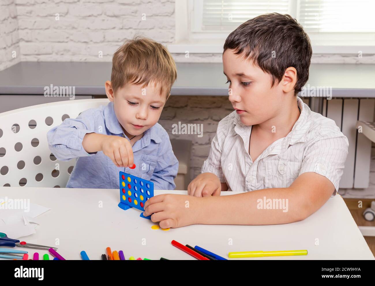 I fratelli carini stanno giocando un gioco da tavolo sulla scrivania a casa Foto Stock
