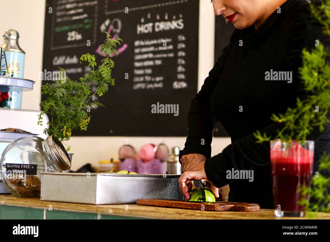 Un lavoratore dedicato o un imprenditore che prepara diligentemente il cibo dietro il bancone di un bar moderno o di un ristorante salutare. Foto Stock