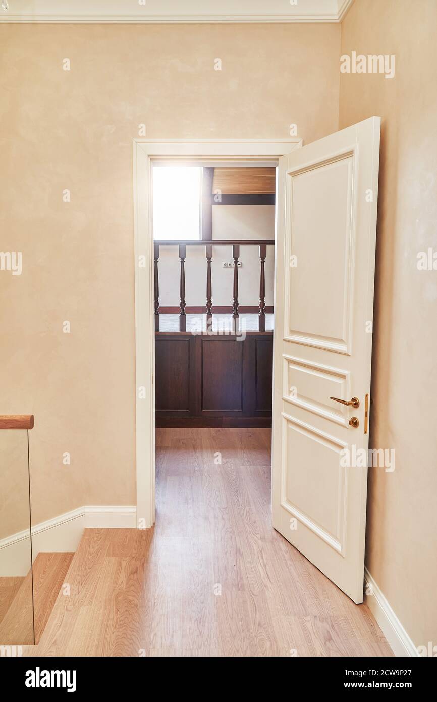 Porta bianca in stile classico. Aperta porta bianca alla biblioteca con balaustra in legno. Porta bianca classica con maniglia dorata Foto Stock