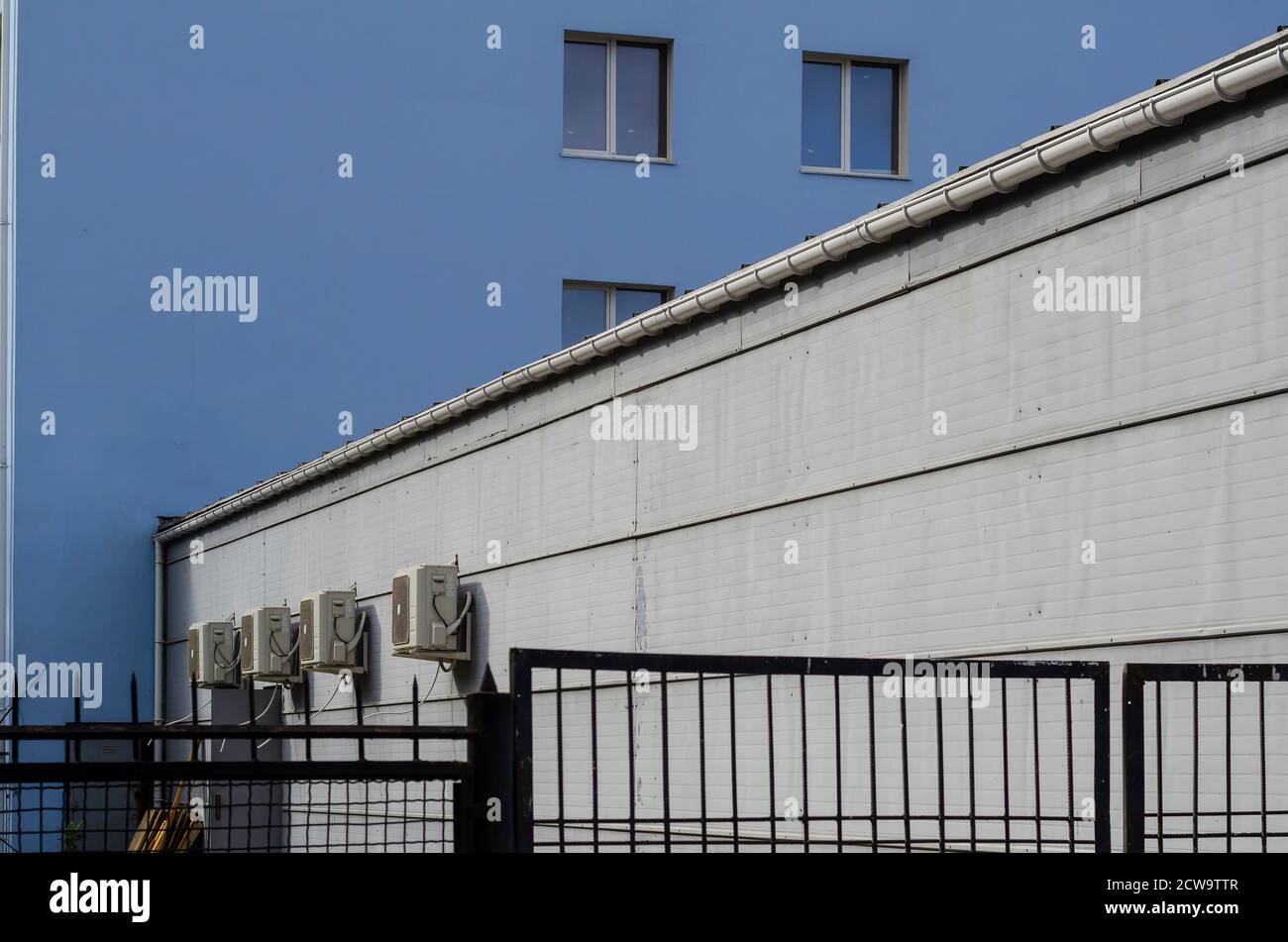 Parete del cortile con unità di climatizzazione. Area protetta dietro una recinzione metallica nera. Vita in città. Senza nessuno Foto Stock