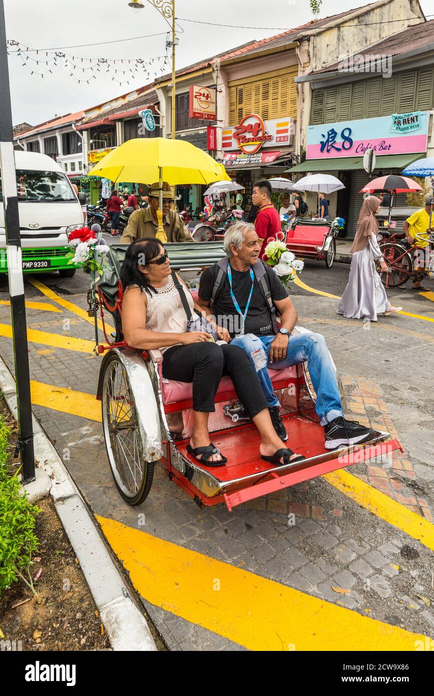 George Town, Penang, Malesia - 1 dicembre 2019: Classico risciò locale con turisti in tempo nuvoloso in via Lebuh Armeno, George Town, Penang Foto Stock
