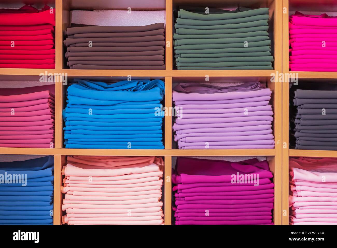 guardaroba in legno con diversi colori mostra abiti in un negozio di abbigliamento. Foto Stock