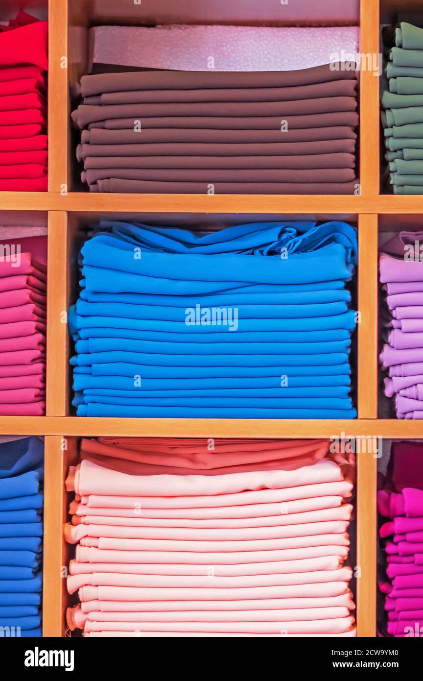 guardaroba in legno con diversi colori mostra abiti in un negozio di abbigliamento. Foto Stock