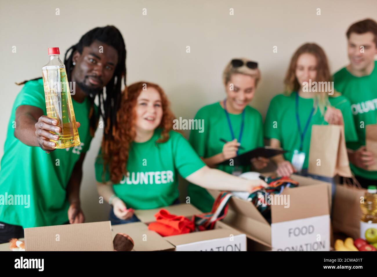un volontario africano affabile dà olio di girasole per gli uomini poveri, tutto ciò di cui hanno bisogno, organizzazione benefica Foto Stock
