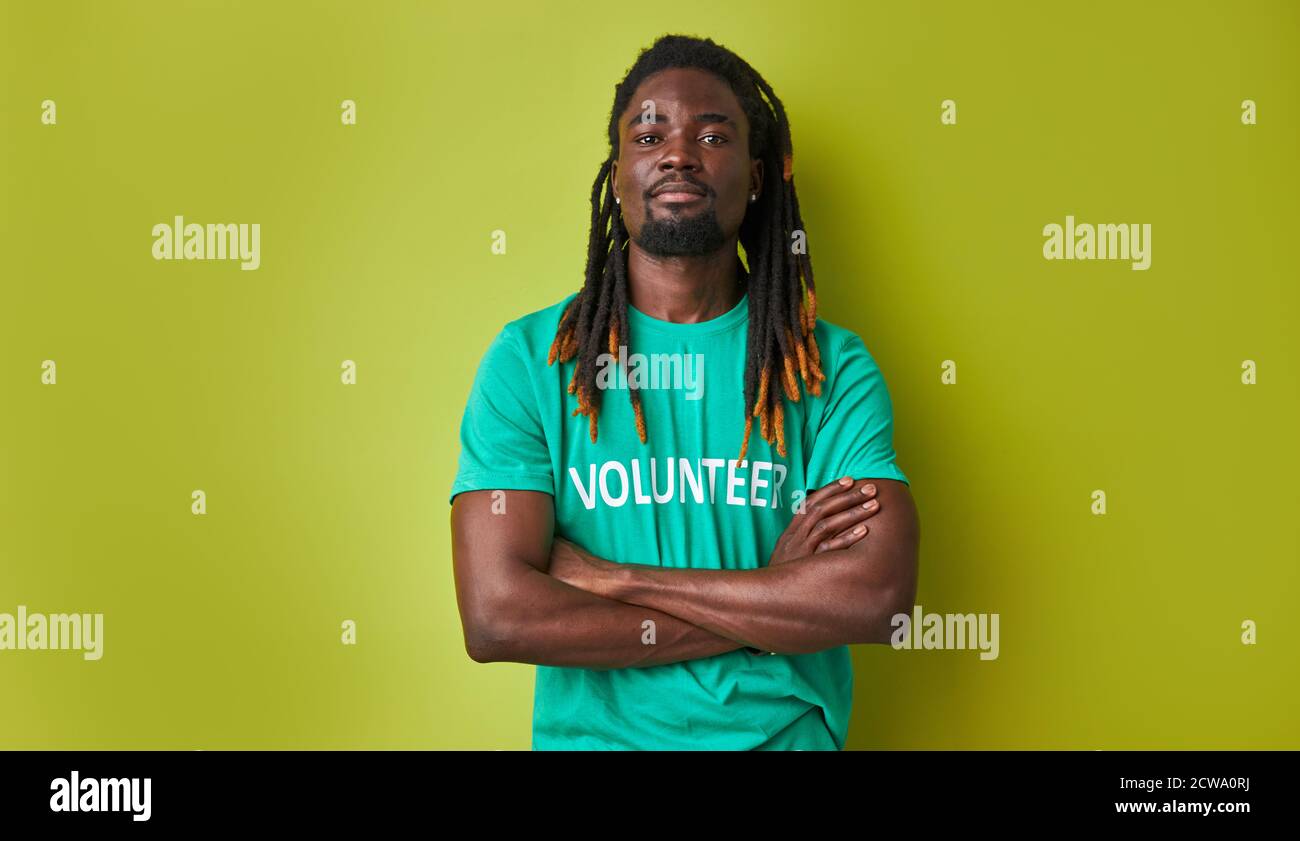 ritratto di bel ragazzo volontario africano in t-shirt verde, giovane uomo sicuro guardare macchina fotografica posa, isolato su sfondo verde Foto Stock