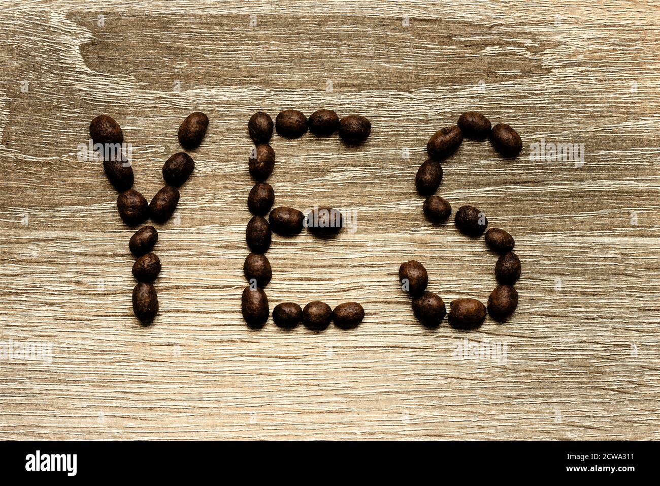 La parola "Sì" è riportata con i chicchi di caffè arabica tostati su un tavolo di legno. Foto Stock