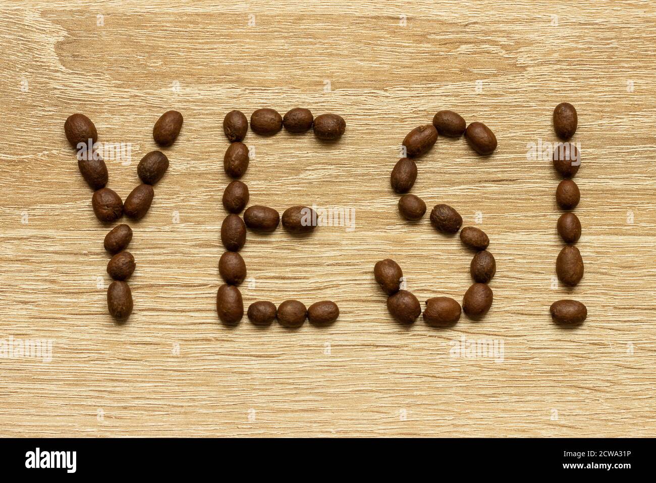 La parola "Sì" è riportata con i chicchi di caffè arabica tostati su un tavolo di legno. Foto Stock