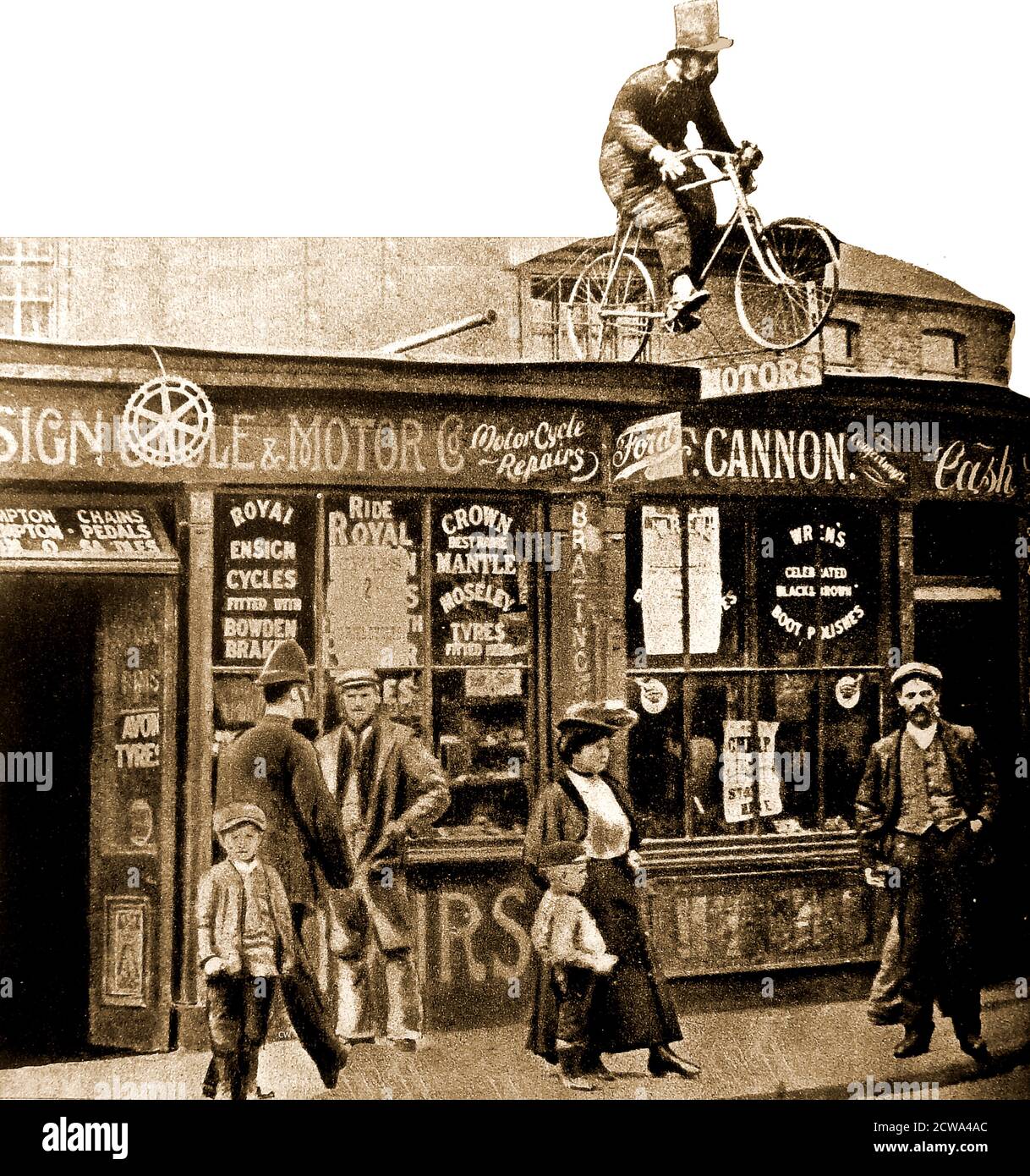 1908 - un depot iniziale di moto e moto a Mitcham, (un'area ora all'interno del London Borough of Merton) UK, completo di un insolito ma realistico segno ciclistico. Nella finestra sono presenti annunci per pneumatici Crown, mantle & Moseley; Royal Ensign Cycles; Bowden Brakes; Avon. Il locale accanto (F Cannon) sembra essere un negozio di articoli da collezione, ma vende anche scarpe da calcio Wrens. Foto Stock