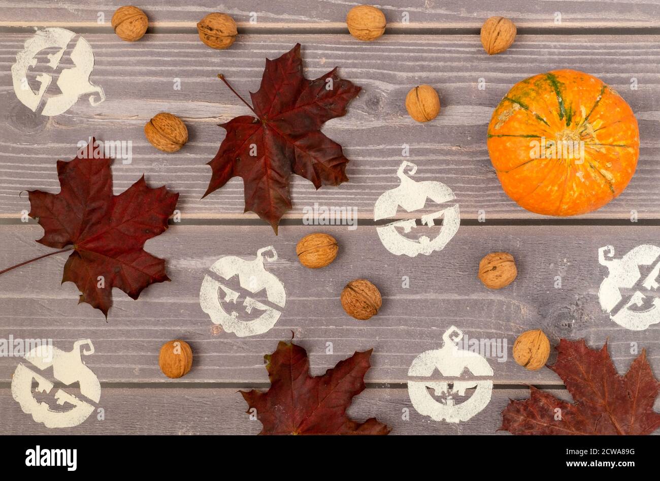Sfondo di Halloween di zucca matura, foglie di acero rosso caduto e simboli di Halloween stenciled su una superficie di legno. Orientamento orizzontale, sele Foto Stock