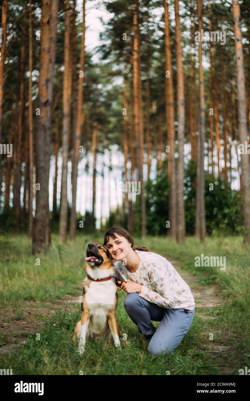 Giovane adulto caucasico donna in posa e sorridente con cane animale domestico in Estate Foresta Verde. Stile di vita sano attivo sulla natura Foto Stock
