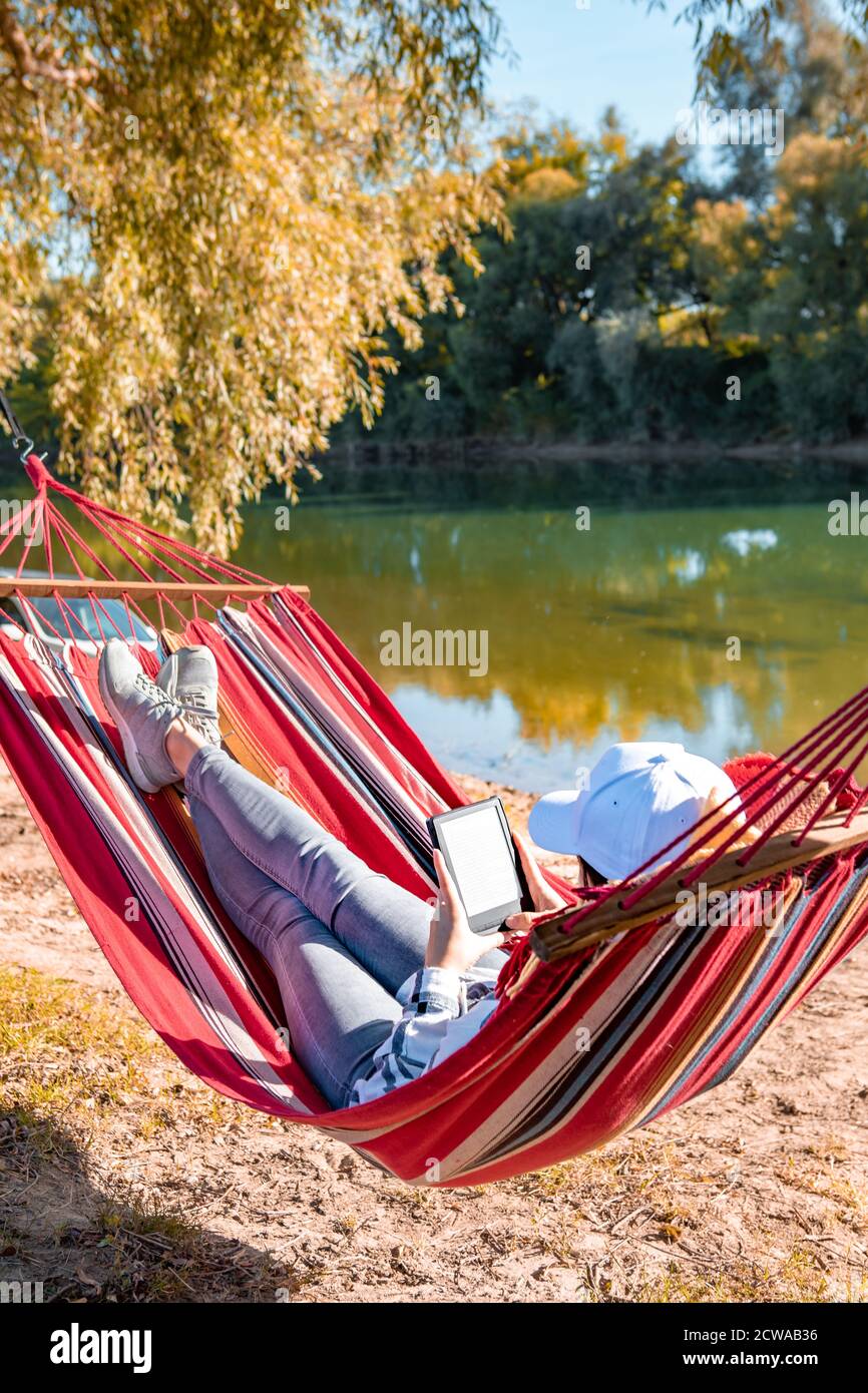 donna lettura libro che posa su amaca all'aperto a river beach Foto stock -  Alamy